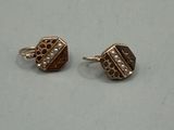 pair of gold tone earrings with diamonds on them on a white surface
