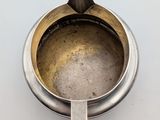 a silver cup with a spoon in it on a white surface