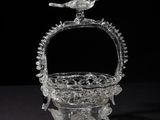 an old glass basket with a bird sitting on top of it