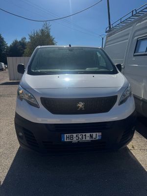 La camionnette blanche est garée sur le parking, à côté d'une autre camionnette blanche.