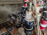 several buckets of paint are stacked on a pallet in a garage