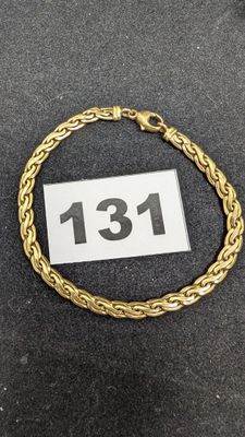 gros plan d'un bracelet en or sur une surface noire