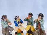 trois figurines représentant des hommes assis sur une surface blanche