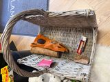 un panier en osier posé par terre, contenant des peluches et d'autres objets