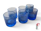 four blue glasses are lined up in a row on a white surface