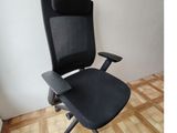 une photo d'une chaise de bureau noire posée sur un parquet en bois massif