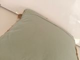 a green pillow with fringes on it on a bed
