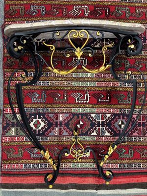 CONSOLE en fer forgé laqué doré ; dessus de marbre rose.