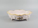 a small white bowl with yellow trim and flowers on it