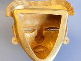 a gold mask hanging on the wall of a room