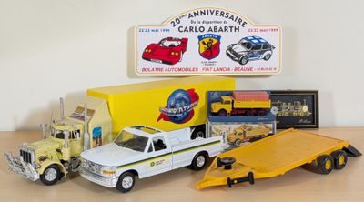 a toy truck with a flatbed trailer and other toy vehicles on a table