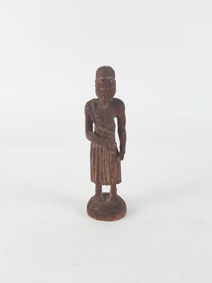 an old wooden statue of a person standing on a white surface