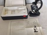 un microscope posé sur une table, à côté d'une feuille de papier