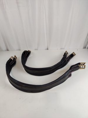 une paire de sangles de bagage en cuir noir posées sur une table blanche