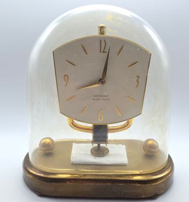une horloge placée sous un dôme en verre, posée sur une table