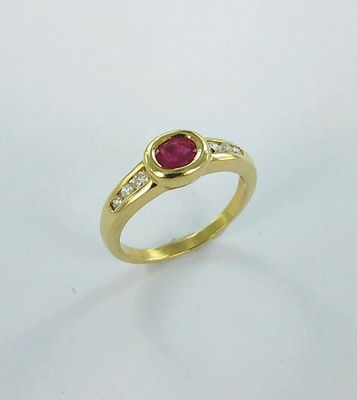gros plan d'une bague en or avec un rubis et des diamants