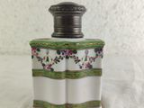 a white and green vase with flowers on it on a table
