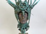 sculpture représentant une tête d'homme avec des cornes, posée sur un socle en bois