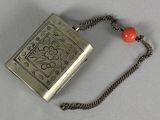 a silver flask with a red bead on a chain