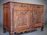 une vieille armoire en bois dont les portes et les tiroirs sont ornés de sculptures
