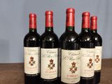 four bottles of red wine are lined up on a wooden table
