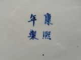 une assiette bleue et blanche sur laquelle figurent des caractères chinois