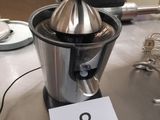 un presse-agrumes en argent posé sur une table sur laquelle figure le chiffre 8