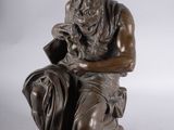 statue of a man sitting on a stool holding a book
