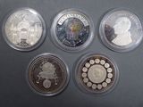 six different coins in a display case on a black surface