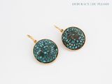 a pair of turquoise and gold earrings on a white background