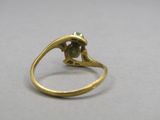 gros plan d'une bague en or avec une pierre verte