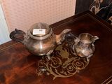 two silver teapots sitting on a wooden table