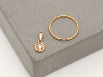 an image of a gold ring and a diamond pendant on a grey surface