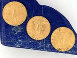 trois pièces d'or posées sur un morceau de marbre bleu