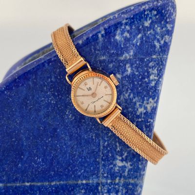 an image of a wrist watch sitting on a blue vase