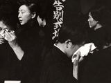 photographie en noir et blanc d'un groupe de personnes debout autour d'une table