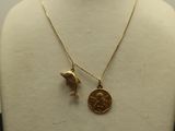 a close up of a necklace with a bird and a coin on a mannequin