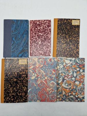six notebooks lined up on a table with a white background