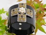 a black bracelet with pearls and a cross on it