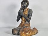 statue représentant un homme assis par terre, les mains jointes sur la poitrine