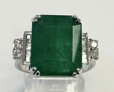 gros plan d'une bague avec une pierre verte entourée de diamants