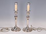 pair of silver plated candlesticks with candles on each of them