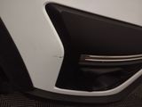 the front end of a white car with black trims and a door handle