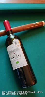 une bouteille de vin posée sur une table de billard, à côté d'une queue de billard