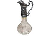 un pichet en verre muni d'une poignée en métal, sur fond blanc