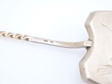 a silver spoon with a handle on a white surface