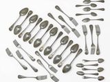 many forks and spoons laid out on a white surface