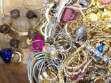a wooden bowl filled with lots of jewelry on top of a table