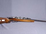 Le fusil est posé sur la table, à côté du chapeau.