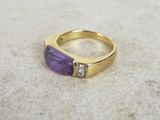 an image of a gold ring with a purple stone and two diamonds